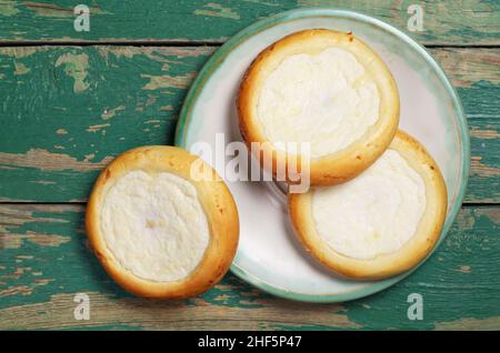 Brötchen mit Quark in Teller auf altem grünen Holzhintergrund, Draufsicht Stockfoto