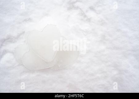 Haufen Herzen - ein Symbol der Liebe, aus Eis, liegen auf dem Schnee. Valentinstag. Romantisches Konzept. Speicherplatz kopieren. Stockfoto