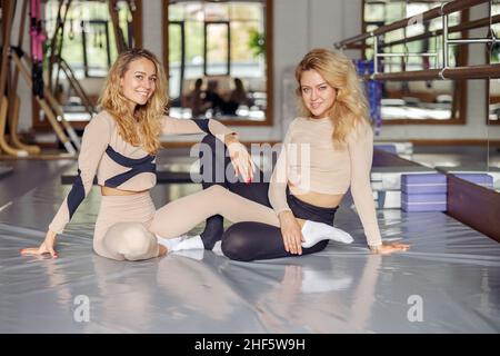 Hübsche junge blonde Frauen lächeln vor der Kamera, während sie nach dem Pilates-Training im Studio posieren. Aktives und gesundes Lifestyle-Konzept Stockfoto