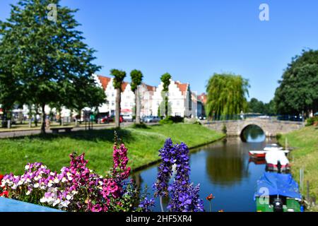 Schöne Blumen und im Hintergrund die Altstadt von Friedrichstadt mit einem Kanal Stockfoto