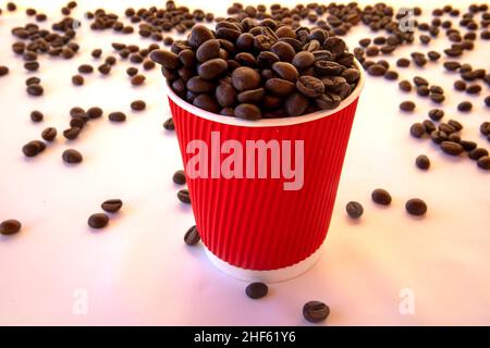 Rote Papiertasse mit Kaffeebohnen auf weißem Hintergrund Stockfoto