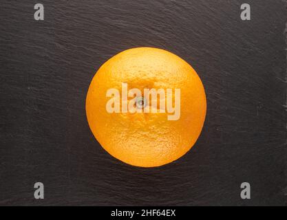 Eine saftige Orange auf einem Schieferstein, Makro, Draufsicht. Stockfoto