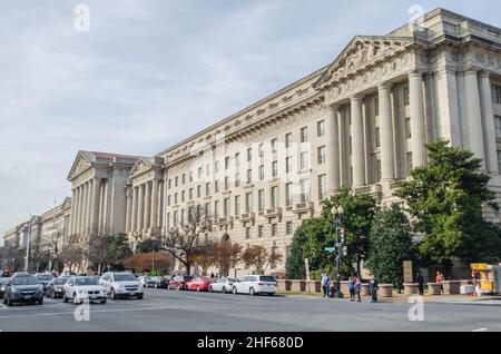 Fassade eines Gebäudes im griechischen Stil mit stolz wehender amerikanischer Flagge. Verkehr auf der Straße vor dem Gebäude. Urbane Straßenfotografie in Washington DC Stockfoto