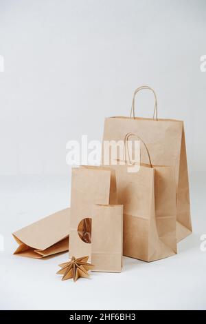 Eine Reihe von Papiertüten, die auf weißem Hintergrund größer werden. Zusammensetzung. Umweltfreundliche kompostierbare Verpackung. Stockfoto