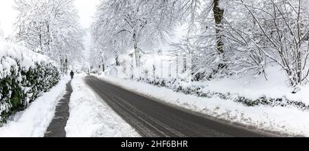 Landstraße mit Bürgersteig im Winter mit Schnee Stockfoto