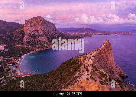Rosa Sonnenuntergang in Novyi Svit im Herbst mit Mount Falcon im Hintergrund. Sudak, die Republik Krim. Luftaufnahme. Stockfoto