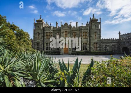 Voronzow-Palast - Alupka, Krim vor dem Hintergrund des blauen Himmels. Leuchtend grüne Büsche und Bäume stehen im Vordergrund und schmecken nach einer Komposition. Stockfoto