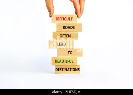 Motivationssymbol. Blöcke mit Worten schwierige Straßen führen oft zu schönen Zielen. Schöner weißer Hintergrund, Kopierbereich. Geschäftsmann Hand. Stockfoto