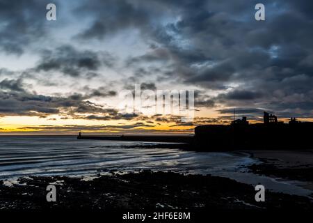 Wunderschöner Sonnenaufgang in Tynemouth's King Edward's Bay mit dem Sonnenlicht, das die Unterseite der Wolken einfängt Stockfoto