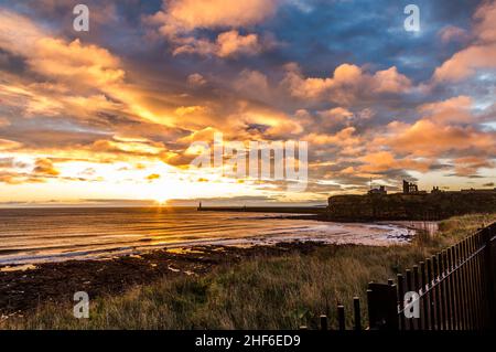 Wunderschöner Sonnenaufgang in Tynemouth's King Edward's Bay mit dem Sonnenlicht, das die Unterseite der Wolken einfängt Stockfoto