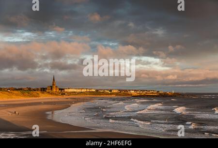 Das erste Licht auf Tynemouth's Longsands Beach, mit Surfern und Hundespaziergängern, die einen schönen Start in den Tag genießen Stockfoto