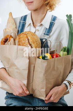 Zugeschnittenes Bild einer Frau, die Papiersäcke mit Gemüse und Gebäck hält Stockfoto