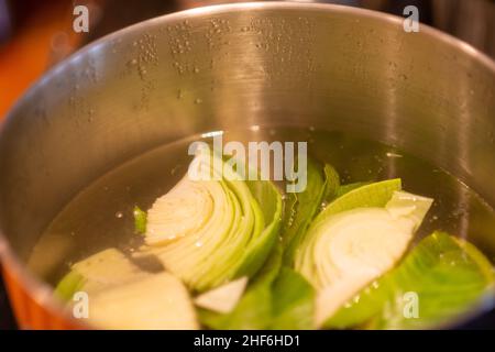 Eine Ansicht von oben auf einen Edelstahltopf gefüllt mit kochendem Wasser, und schneiden Stücke von Bio-Kohl Kochen auf einem Restaurant Herd. Stockfoto