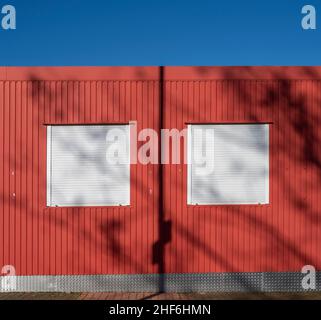 Rotes Gebäude, weiße Jalousien, Schatten, blauer Himmel, Rot-Weiß Oberhausen Stockfoto