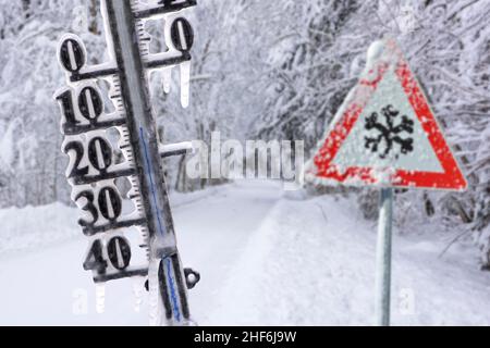 Das Thermometer zeigt kalte Temperaturen und Eiszapfen im Winter auf rutschiger Straße an Stockfoto