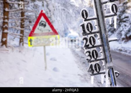 Das Thermometer zeigt kalte Temperaturen und Eiszapfen im Winter auf rutschiger Straße an Stockfoto