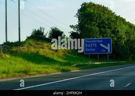 Blaues britisches Autobahnschild mit Platz für Text auf der Autobahn A1, das Verkehrsteilnehmer in Richtung Piercebridge und Barton führt, B6265. Kreuzung. Tra Stockfoto
