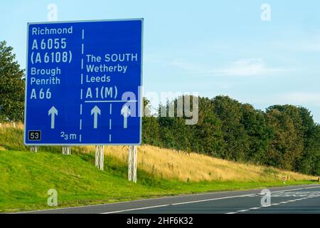 Leeds, Großbritannien - 23rd. August 2019: Autos fahren auf der britischen Autobahn A1 mit blauen Autobahnschildern, die die Fahrer nach Richmond, Leeds, Brough, Wetherby, Stockfoto