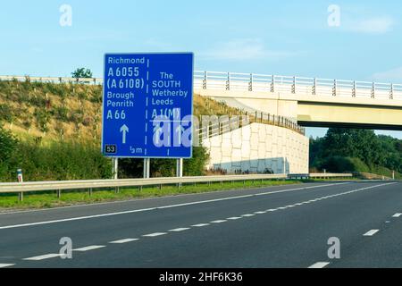 Leeds, Großbritannien - 23rd. August 2019: Autos fahren auf der britischen Autobahn A1 mit blauen Autobahnschildern, die die Fahrer nach Richmond, Leeds, Brough, Wetherby, Stockfoto