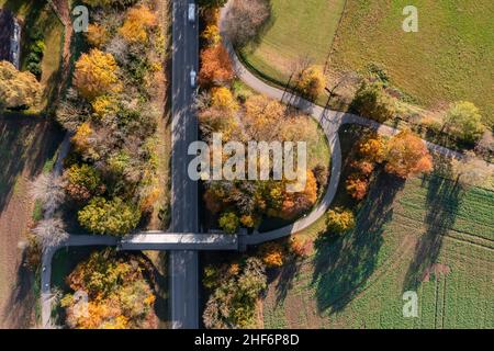 Blick von oben auf eine herbstliche Landschaft mit einer Landstraße und einer überdachten Brücke für Pedestiner direkt von oben in Oberhaching Stockfoto