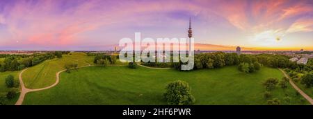 Traumhafter Sonnenaufgang über dem beliebten Olympiapark von München aus, mit einem Panoramablick über den Sightseeing-Hotspot der bayerischen Hauptstadt und einem violetten Morgenhimmel Stockfoto