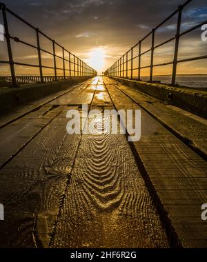 Eine Nahaufnahme einer strukturierten Holzplanke auf dem alten hölzernen Pier, der sich an einem herrlichen Morgen am Blyth Beach bis zur Nordsee erstreckt Stockfoto