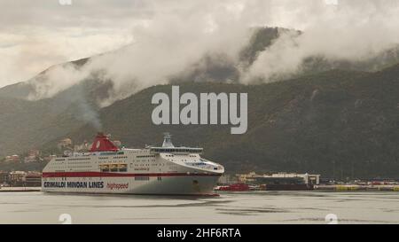 Griechenland, griechische Inseln, Ionische Inseln, Korfu, Fährüberfahrt, Hafen von Igoumenitsa, grauer Himmel, Regen, Wolken hängen tief über Igoumenitsa, eine große italienische Fähre der Minoan Lines vor Anker, im Hintergrund üppig grüne Hügel Stockfoto