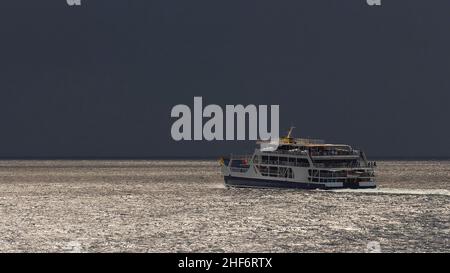 Griechenland, griechische Inseln, Ionische Inseln, Korfu, Fährüberfahrt, Kleine Fähre von Korfu nach Igoumenitsa, silbrig glitzerndes Meer, sehr schwarzer Himmel, Gewitterstimmung Stockfoto