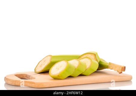 Eine halbe und vier Scheiben organische grüne Banane auf einem Holzschneidebrett, Nahaufnahme, isoliert auf Weiß. Stockfoto