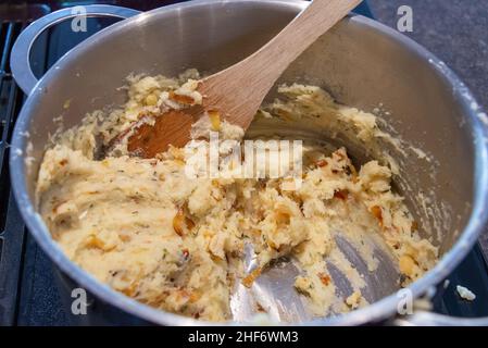 Zum Braten wird ein Topf mit ungekochten Salz-Kabeljau-Fischkuchen zubereitet. Die Mischung aus Bohnenkraut, Kartoffeln, Salz-Kabeljau und Butter wird zu kleinen Patties geformt. Stockfoto