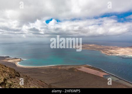 Blick vom Mirador del Rio auf den Salinas del Rio und den einsamen Strand Playa del Risco, direkt hinter der Insel La Graciosa, Lanzarote, Kanaren, Kanarische Inseln, Spanien, Europa Stockfoto