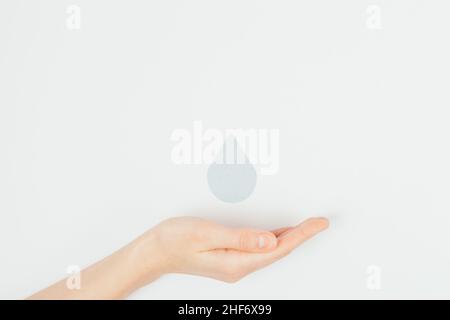 Save Water Concept weibliche Hand hält Tropfen auf weißem Hintergrund, flach liegend. Weltwassertag Stockfoto