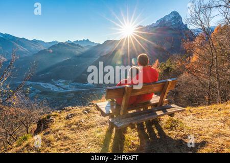 Zwei Personen (Vater und Tochter), die im Herbst auf einer Bank sitzen und den Sonnenuntergang betrachten, Agordo, Provinz Belluno, Venetien, Italien Stockfoto