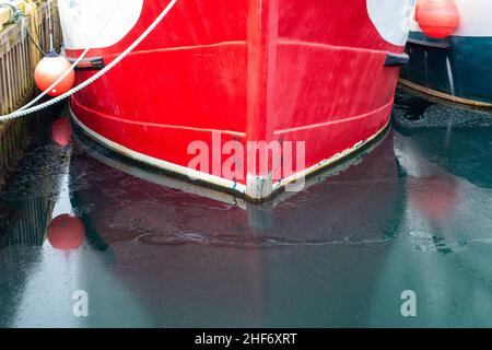 Ein leuchtendes rotes Metallschiff mit schwarzen und weißen Markierungen für die Wasserlinie oder Ladereihen am Rumpf des Schiffes. Das Messgerät hat die Nummern 11,10 und 9. Stockfoto