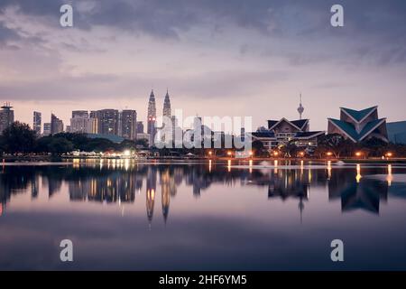 Skyline von Kuala Lumpur im Morgengrauen. Spiegelung von Wolkenkratzern in der Wasseroberfläche. Stockfoto