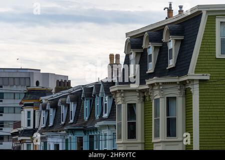 Blick auf die Straße von mehreren farbenfrohen Holzgebäuden in hellen Farben. Die alten Häuser haben doppelhängende Fenster, hippe Dächer und Studentenfenster. Stockfoto