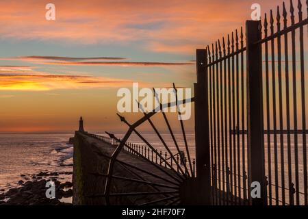 Tynemouth Pier und der Leuchtturm durch die Metallgeländer mit einem wunderschönen, lebhaften Sonnenaufgang Stockfoto