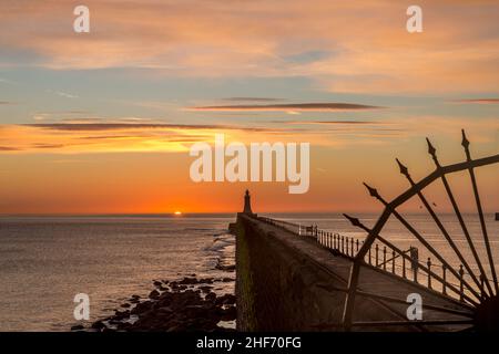 Tynemouth Pier und der Leuchtturm durch die Metallgeländer mit einem wunderschönen, lebhaften Sonnenaufgang Stockfoto