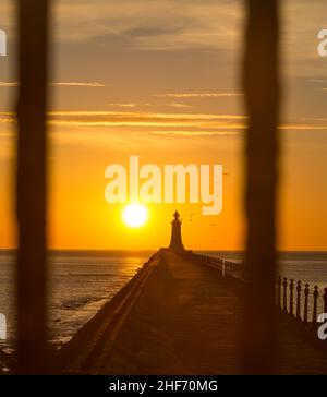 Tynemouth Pier und der Leuchtturm durch die Metallgeländer mit einem wunderschönen, lebhaften Sonnenaufgang Stockfoto