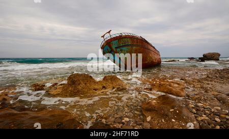 Griechenland, griechische Inseln, Ionische Inseln, Korfu, Westküste, Agios Gordios, schlechtes Wetter, wolkiger Himmel, Schiffswrack, Graffiti-Malerei, Surfen, Weitwinkel, im Vordergrund feste Küste und Meer, grauer Himmel, Wrack ist an der Küste Stockfoto