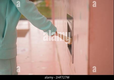 Eine Frau wirft einen Kraftpapierbeutel in eine Müllkippe in einer Cafewand. Stockfoto
