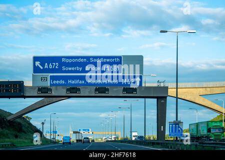 Leeds, Großbritannien - 19th. Juni 2019: Ein blaues britisches Autobahnschild über der Autobahn, das den Verkehr in Richtung Leeds, Huddersfield, Halifax, M62, Ripponden, Stockfoto