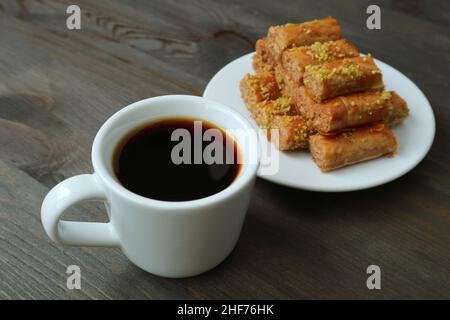 Nahaufnahme eine Tasse türkischen Kaffee mit verschwommenem Teller Baklava-Gebäck im Hintergrund Stockfoto