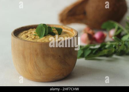 Kokosnuss-Chutney. Würzige Würze aus frischen Kokosnüssen, roten Chilischoten und Schalotten. Serviert in einer Holzschüssel. Ein Begleiter für knusprigen Topfkuchen. Aufnahme Stockfoto