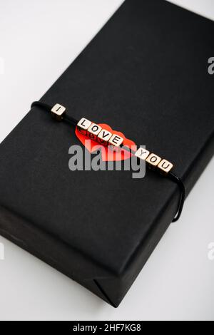 Valentinstag Geschenkverpackung, Paket. Valentinstag Geschenk Hintergrund mit schwarzem Handwerk Geschenkbox mit Text I Love You und zwei roten Papier Herzen. Stockfoto