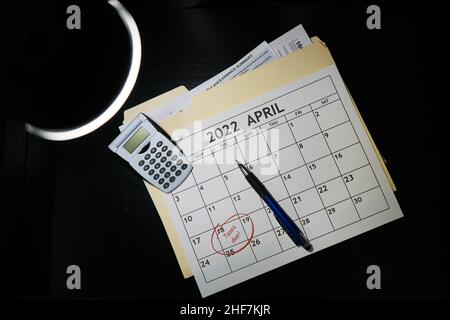 Konzept von 2021 Steuervorbereitungsdokumenten und einem Kalender mit April 18th umkreist das Wort fällige Steuern rot. Auf schwarzem Hintergrund. Stockfoto