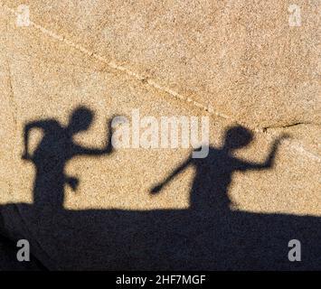 Kinder spielen mit Schatten auf einem Felsen im Juschua Tree Nationalpark Stockfoto