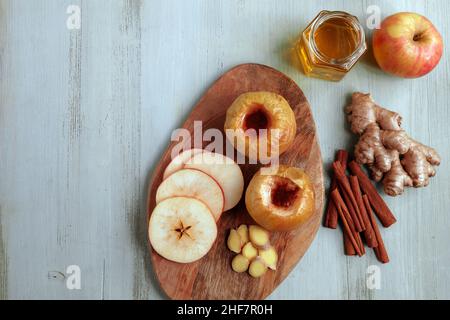 Gebackener Apfel mit Honig, Zimt und Ingwer auf einem hellen Holztisch Stockfoto