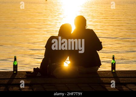 Rostock, Paar am Kai, Sonnenuntergang, Bierflaschen in Ostsee, Mecklenburg-Vorpommern, Deutschland Stockfoto