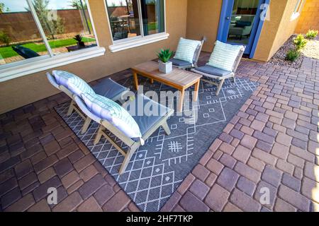 Hinterer Patio-Wohnbereich Mit Holztisch, Vier Stühlen Mit Kissen Und Dekorativem Teppich Stockfoto